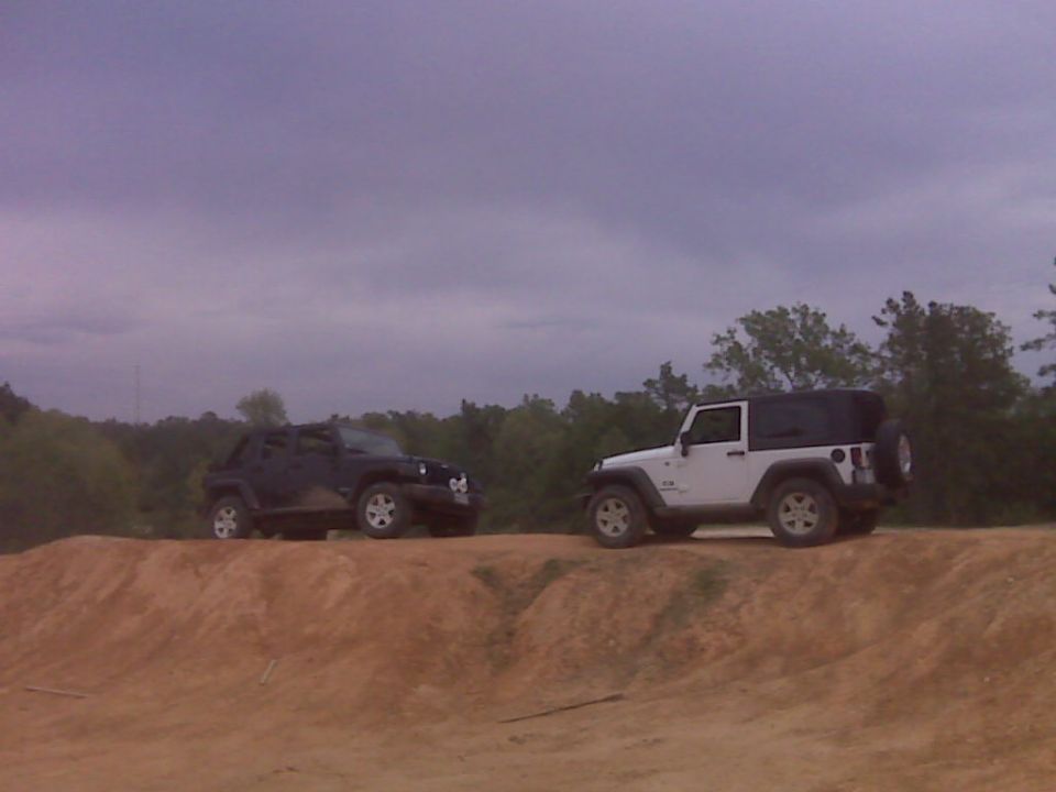 White Jeep Wrangler and black Jeep Wrangler on dirt hill