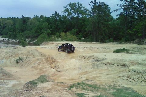 2008 Jeep Wrangler - A Jeep Wrangler navigates a challenging off-road terrain with trees and a river in the background.