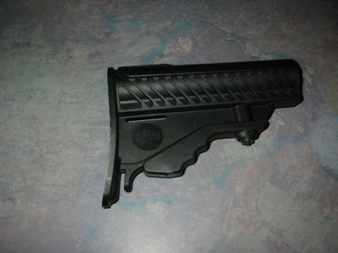 1996 Ford Bronco - A black gun stock is shown against a textured background. The part has a textured buttpad and a circular emblem.