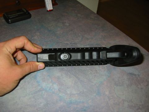 1996 Ford Bronco - A black plastic part with a silver lock mechanism is held by a hand over a textured surface.