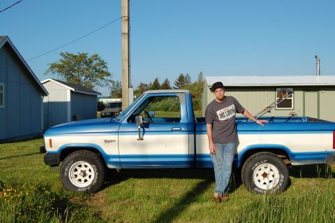 1985 Ford Ranger - A man stands next to a blue and white Ford Ranger pickup truck on a sunny day.
