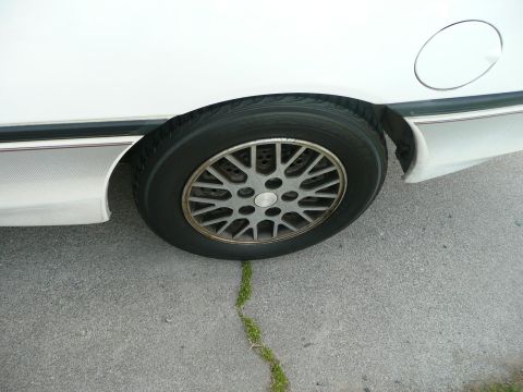 1989 Ford Probe - Close-up of a white car's rear wheel and part of the body, showing the fender and gas cap door.