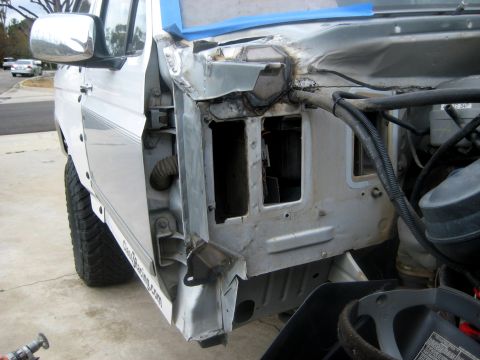 1996 Ford Bronco - Passenger-side view of a white Ford truck in a driveway with the front fender off, showing the bare inner fender panel and cowl area with f…