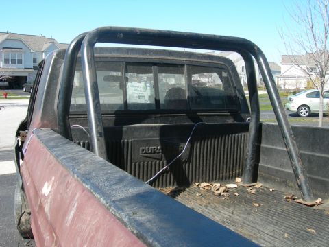 1985 Ford Bronco - Rear view of a pickup truck bed a roll bar and 'Dura' text on the tailgate.