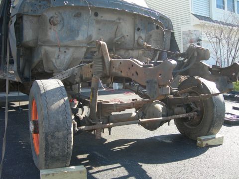 1985 Ford Bronco - Disassembled truck chassis with front suspension components and wheels visible.