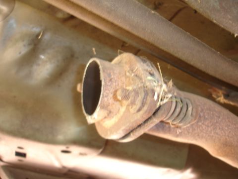 1995 Ford Taurus - Underside view of a rusty exhaust pipe, showing signs of wear and tear.