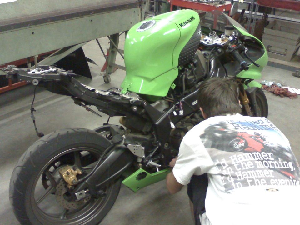 Green 2005 Kawasaki Ninja R motorcycle with fairings removed, being worked on by a person. Kawasaki logo visible on the tank