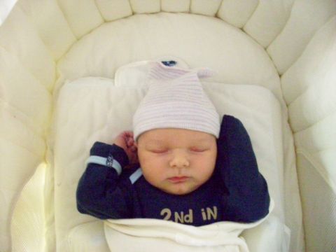 1997 Ford Probe - Baby sleeping soundly in a crib, wearing a striped hat and a sleepsuit with text on the front.