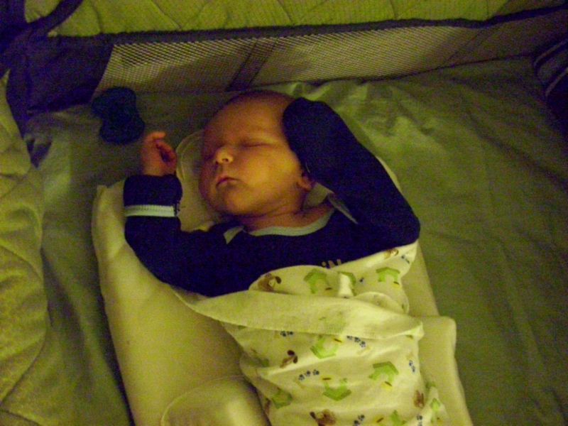 Baby sleeping in a crib, wrapped in a blanket with cartoon animals
