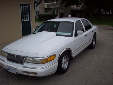 1992 Mercury Grand Marquis - This white 1992 Mercury Grand Marquis features a prominent hood scoop and chrome accents.