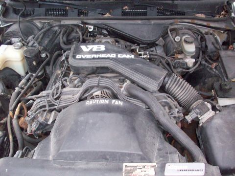 1992 Mercury Grand Marquis - The engine bay of a vehicle, a V8 Overhead Cam engine cover and a "CAUTION FAN" warning.
