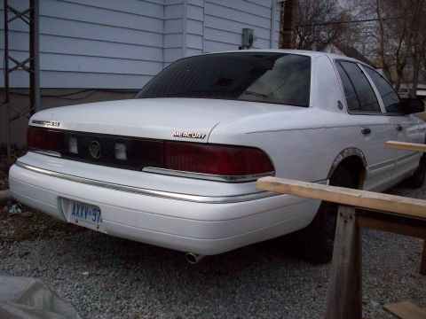 1992 Mercury Grand Marquis - The rear of a white Mercury Grand Marquis is visible, with the license plate reading AXXV-97.