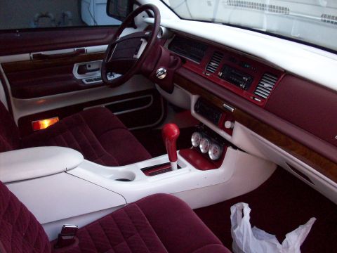 1992 Mercury Grand Marquis - The interior of a 1992 Mercury Grand Marquis features maroon velour upholstery, wood grain accents, and a column shifter.
