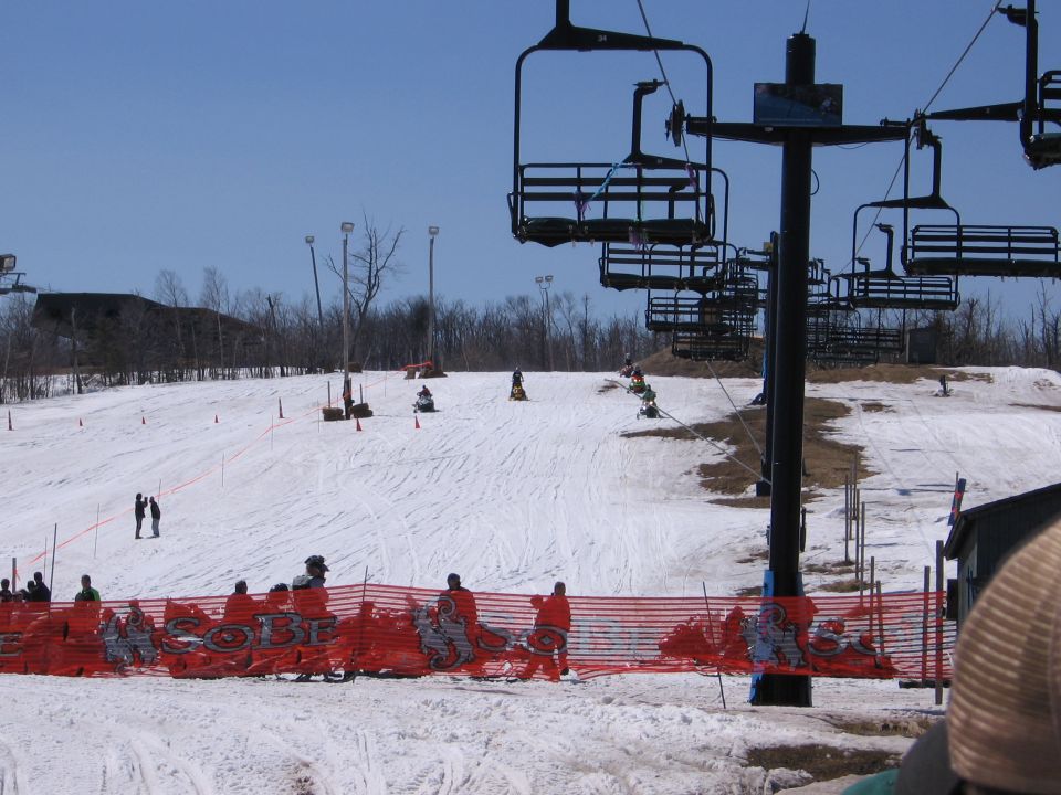 Ski hill with chairlift and snowmobiles under orange safety fence