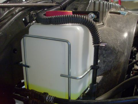 1978 Ford Bronco - Close-up of a vehicle's engine bay, focusing on the windshield washer fluid reservoir and associated components.