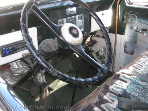 1968 Ford Mustang - The interior of this vintage vehicle features a classic steering wheel and dashboard, with a distinctive patterned seat cover.