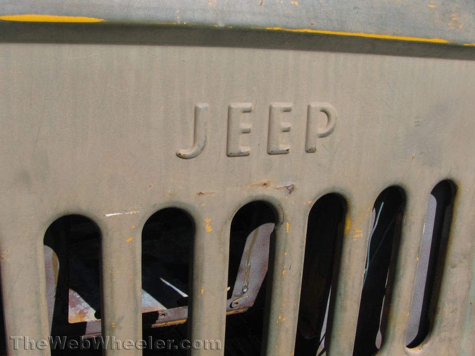 Olive drab Jeep grille with raised lettering and vertical slots