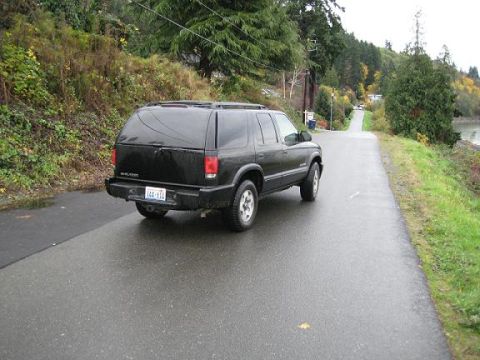 2004 Chevrolet Blazer - Rear view of a black 2004 Chevrolet Blazer driving on a wet road.