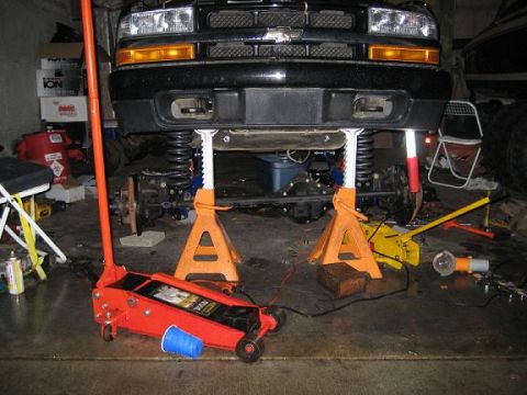 2004 Chevrolet Blazer - Front view of a black 2004 Chevrolet Blazer being worked on, with the front end raised on jack stands in a garage.