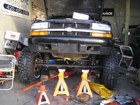 2004 Chevrolet Blazer - This Chevrolet pickup truck is elevated on jack stands for maintenance, with its hood open.