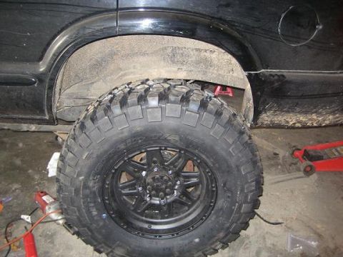 2004 Chevrolet Blazer - A black SUV's rear wheel well is shown with a large off-road tire and black rim, indicating modifications.