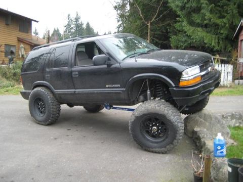 2004 Chevrolet Blazer - This modified Chevrolet Blazer is positioned on rocks, its lifted suspension and large tires.