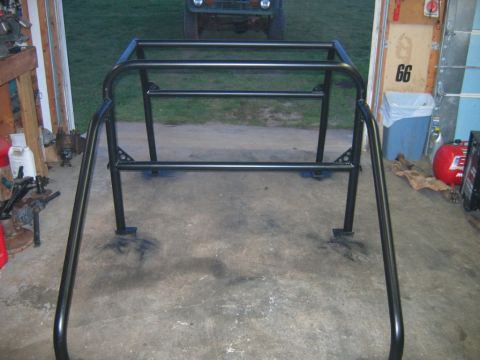 1992 Ford Mustang - A black metal roll cage is shown in a garage setting, with a green vehicle visible in the background.