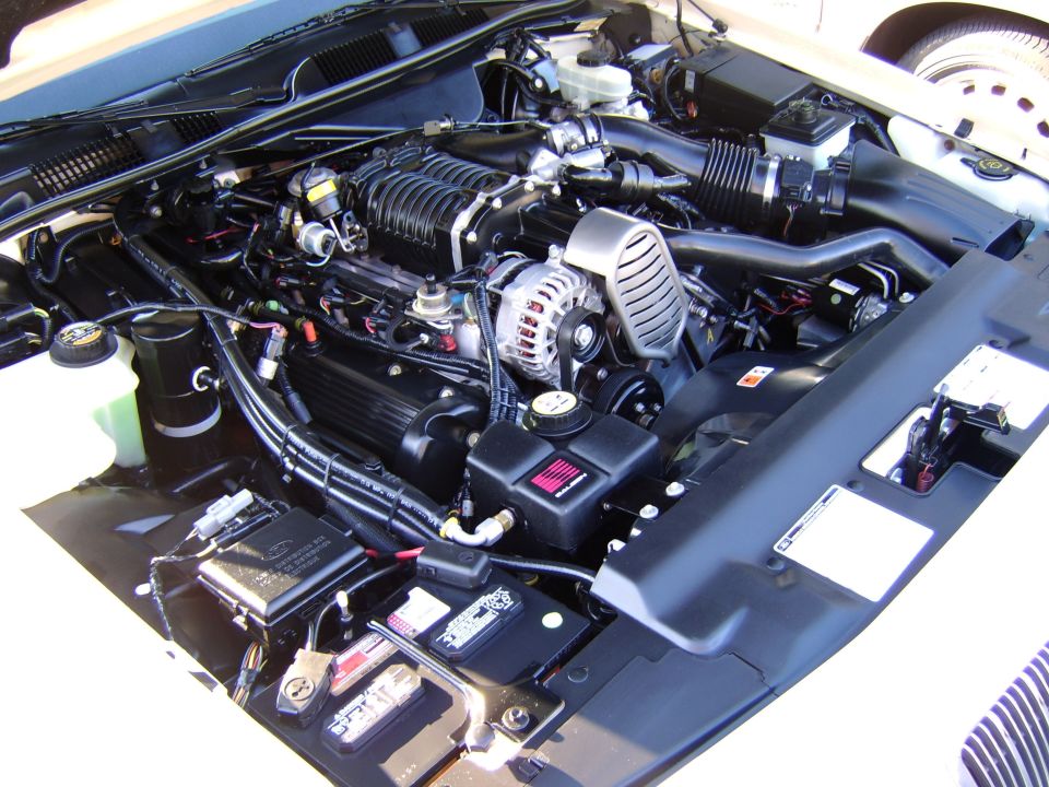 Supercharged V8 engine bay with alternator, black covers and battery