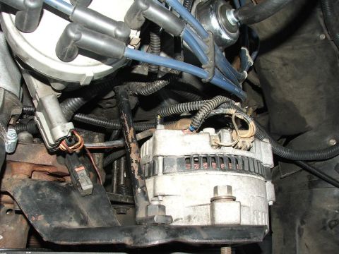 1985 Ford Crown Victoria LTD - Close-up view of an engine's alternator and distributor cap with spark plug wires.