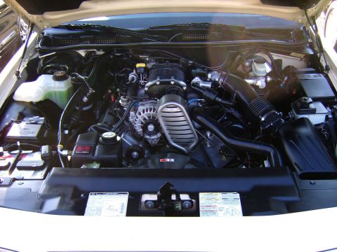 1996 Mercury Grand Marquis - The engine compartment shows a V8 engine with a prominent supercharger and various hoses and components.
