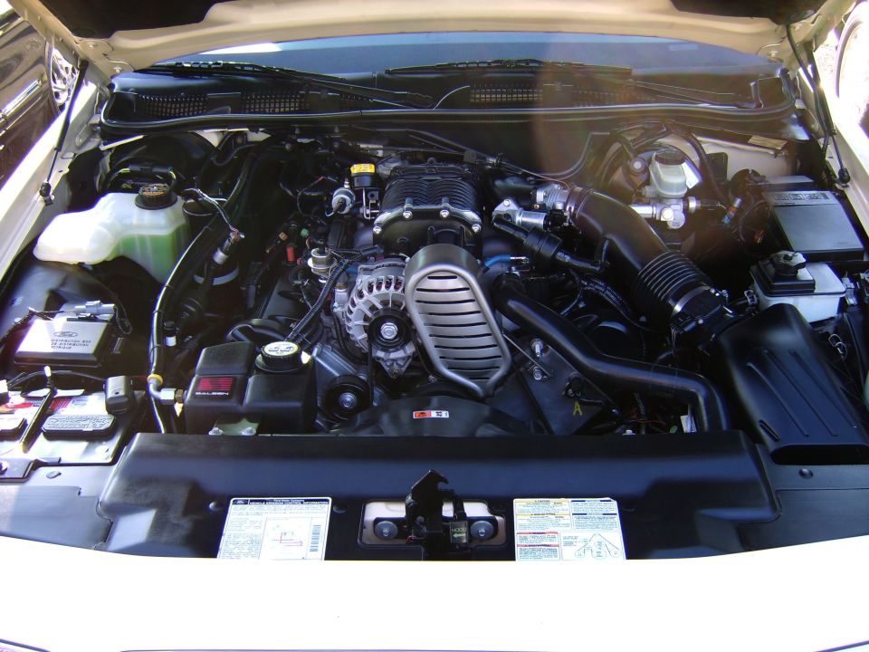 Overhead view of a supercharged V8 engine bay with battery and decals.