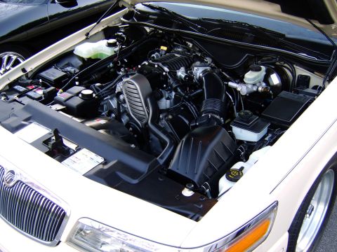 1996 Mercury Grand Marquis - The engine compartment of a 1996 Mercury Grand Marquis is shown with the hood open. A portion of another vehicle is visible in the backgrou…