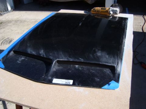 1973 Ford Ranchero - A black car hood with vents is prepared for work, with tools nearby.