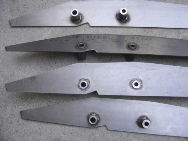four metal brackets with holes and welds, one has text that says 'CRIP STEEL 125 RMS 4150'