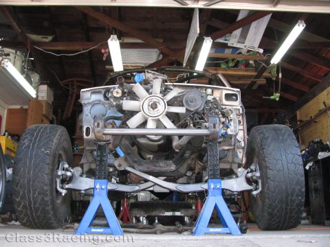 1990 Ford Bronco - Photo of a truck on jack stands showing engine and front suspension in a garage, not a technical document.