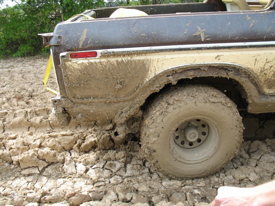 Rear wheel of a brown truck buried in deep mud