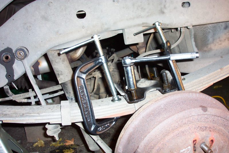 Vehicle leaf spring with C-clamps and a socket wrench tool attached to suspension