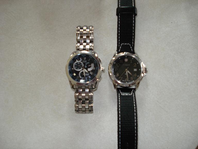 Two watches, one with a metal band and one with a fabric band, on a textured surface.