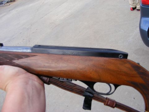 1979 Ford Bronco - A close-up shot of a rifle held by a person's arm. The rifle has a wooden stock and a black receiver with "Weatherby" engraved on it.