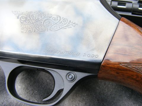 1979 Ford Bronco - A close-up of intricate scrollwork and the text "Browning 2000" engraved on a metallic surface, likely a firearm. The image also shows a po…