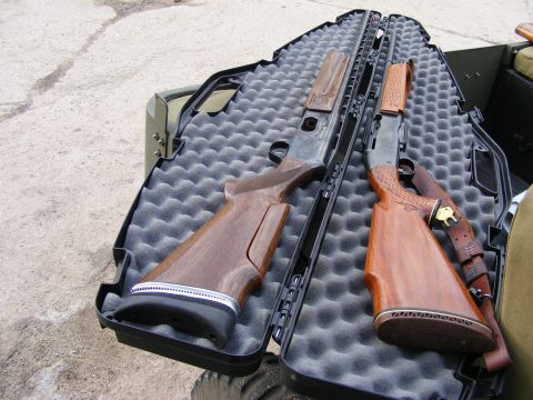 1979 Ford Bronco - Two shotguns are laid out in an open black gun case with gray foam padding. The case is resting on a concrete surface next to a vehicle.