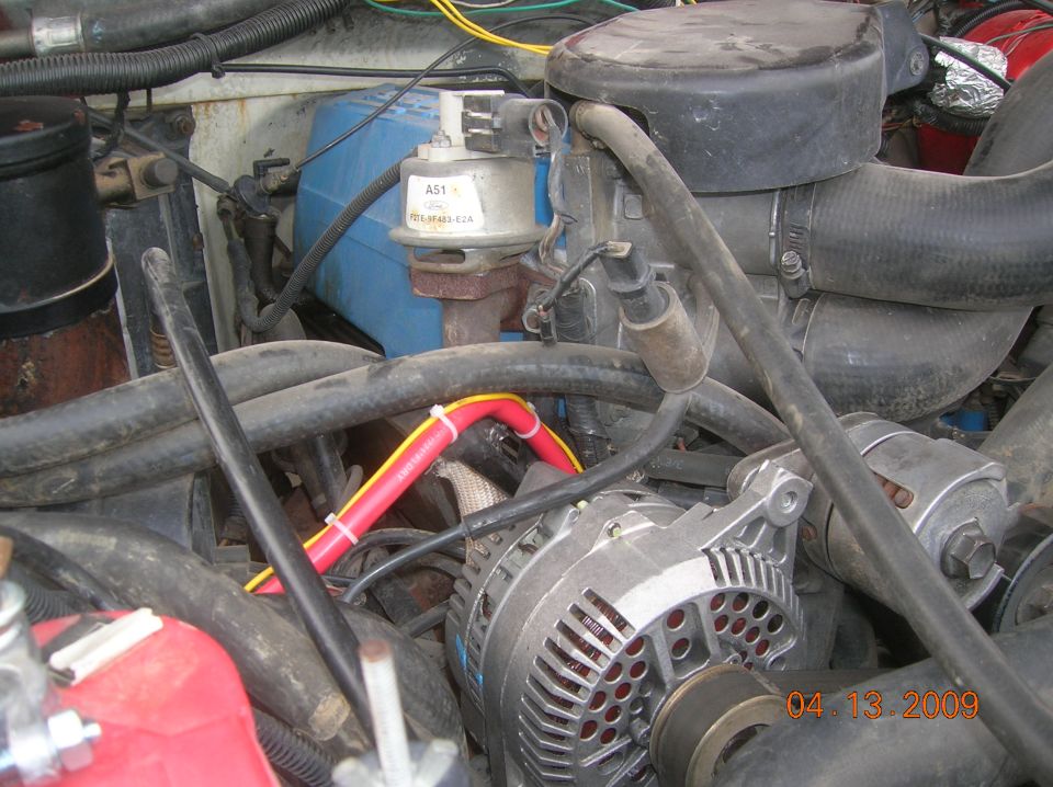 Close-up of Ford Bronco engine bay showing alternator, hoses, and engine parts.