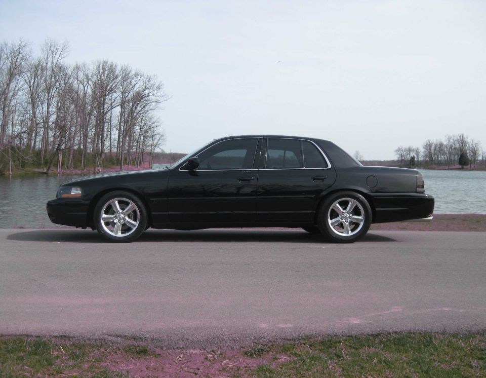 Black four-door sedan parked on a road, side view.