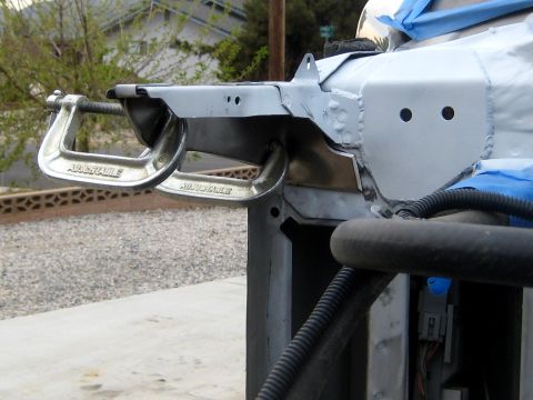 1996 Ford Bronco - Two adjustable C-clamps are holding a metal bracket in place on the front end of a vehicle, likely during a repair or modification. The veh…