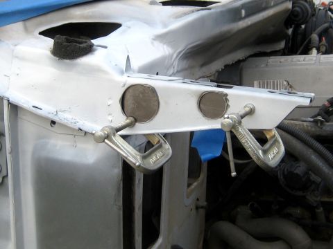 1996 Ford Bronco - A steel reinforcement plate held in position on a vehicle's bare-metal inner fender rail by two C-clamps, with two large round rosette-weld…