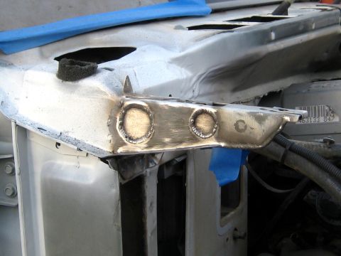 1996 Ford Bronco - Close-up of a steel reinforcement bracket freshly welded onto a bare-metal inner fender apron, with two large rosette welds ground flush an…