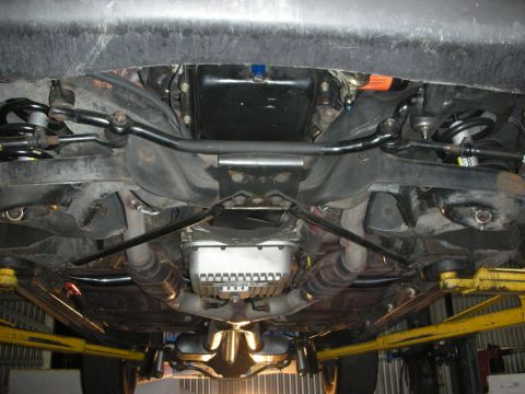 1992 Ford Crown Victoria - Undercarriage view of a 1992 Ford Crown Victoria, showing the front suspension, exhaust system, and transmission pan. The vehicle is suppor…