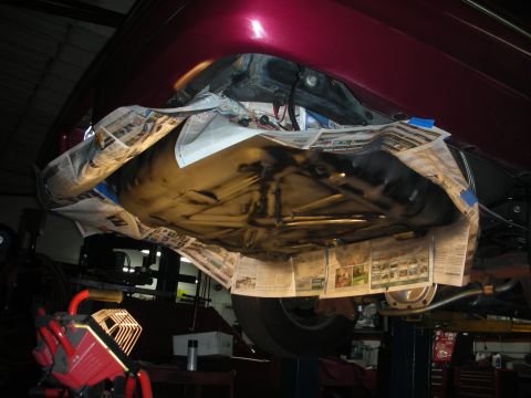 1992 Ford Crown Victoria - The underside of a vehicle is shown, with the fuel tank covered in newspaper for protection during a painting or coating process. The vehic…
