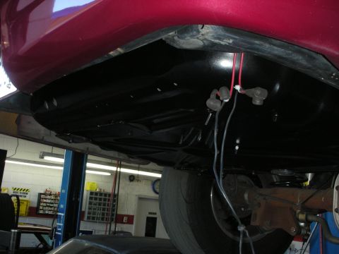 1992 Ford Crown Victoria - Close-up view of the undercarriage of a red vehicle, revealing mechanical parts and wiring.