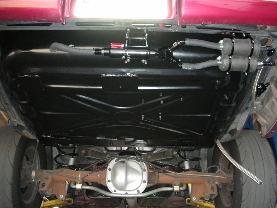 Underbody view of car showing fuel tank, dual fuel pumps, differential, and rear tires